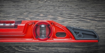 Red construction level on wooden board top view