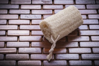 Loofah on textured wooden matting close up view healthcare concept