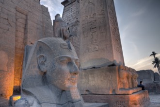 Illuminated entrance of Luxor temple with Ramses II statue and obelisk, Luxor, Egypt