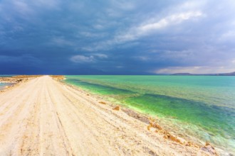 Low winter clouds are reflected in the green sea water. The landfill embankment runs through the