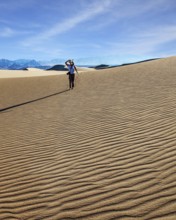 USA. Mesquite Flat Sand Dunes, Death Valley, California. Woman with a camera and a tripod goes