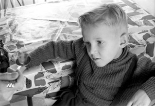 A boy is sick and won't take his medicine. His mother holds out a spoon and waits for him to gape
