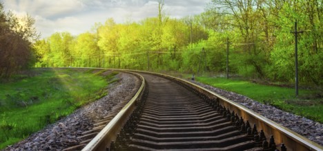 Morning landscape on the railway tracks. The sun's rays are the green grass and the rails on which