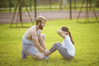 Sit ups fitness couple exercising sit up outside in graß Fit people working out cross training.