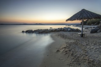 View through rocks on a sandy beach into the sunset. Landscape shot with view to the horizon over