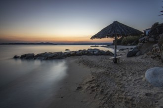 View through rocks on a sandy beach into the sunset. Landscape shot with view to the horizon over