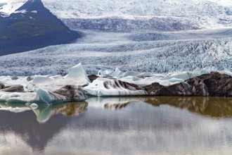 Blocks of ice are reflected in smooth water. Jokulsarlon glacial lagoon. The imposing scenic lagoon