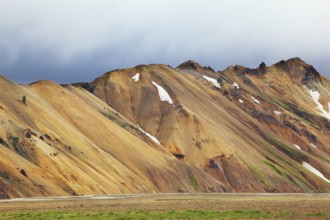 Smooth orange rhyolite mountains in Landmannalaugar nature reserve. In the hollows snow left over