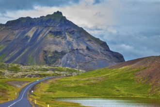 The road passes through the picturesque landscape in the mountains and lakes. Cloud Iceland in the