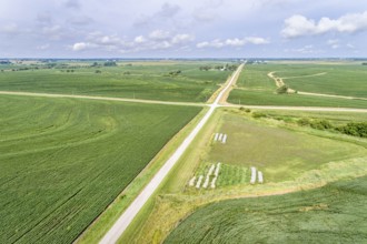 Aerial view of rural Nebraska landscape with a farm road, soybean field and hay bales