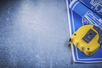 Assortment of blue construction plans measuring tape on metallic background