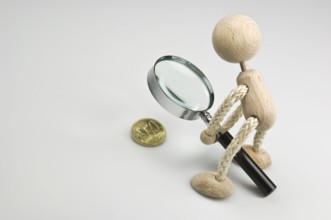 Wooden figure holding a magnifying glass over a 50 euro cent coin, Federal Republic of Germany