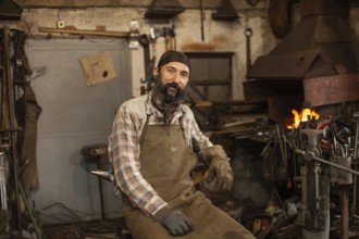 Bearded blacksmith after working in his workshop. Blacksmith's workshop. Professional blacksmith