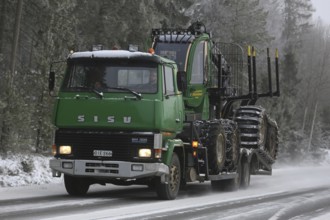 SALO, FINLAND, JANUARY 8, 2017: Green SISU SM300 truck transports a John Deere Forestry forwarder