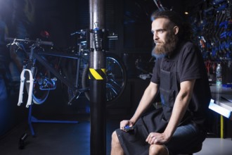 Portrait of small business owner of young man with beard. Guy bicycle mechanic workshop worker