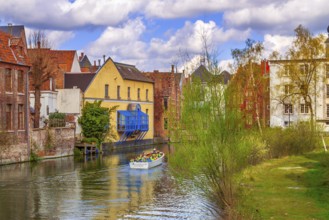 Ghent, Belgium, April 12, 2016: Old houses along canal and boat with tourists in popular touristic