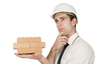 Upper body shot of a young man in a white shirt and white helmet with a stacked wooden block on his