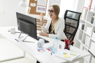 A beautiful young blonde girl in a white jacket and black blouse is working in the office. photo