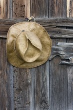 Straw cowboy hat and weathered wood of old barn in Colorado