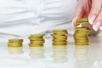 A woman stacks coins. Saving money for the future. Austria
