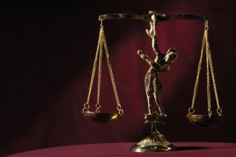 Stock photo of Shiny golden empty balanced vintage justice scales isolated on dark red background