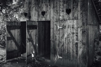 Open doors to old wooden outhouses. Romania