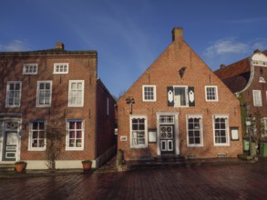 Two brick houses with beautiful façade and balcony under a blue sky, Greetsiel, East Frisia,