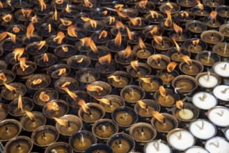 Group of oil religious candles glowing with orange flames on a hindu temple. Symbols of faith and