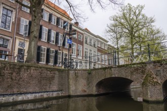 A canal with a stone bridge and historic buildings in the background, bicycles next to the bridge,