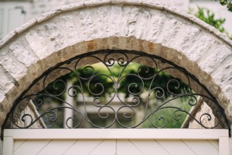 Arched metal forged lattice in a stone fence. Close-up.