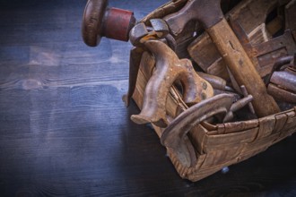 Set of vintage tools in wicker box on wooden board