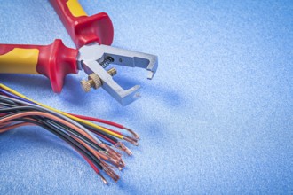 Insulated wire strippers electric cables on blue background electricity concept