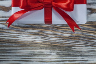 Red present box with ribbon on wooden background