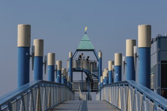 Blue jetty with yellow elements, modern architecture, blue sky, some people on the platform,