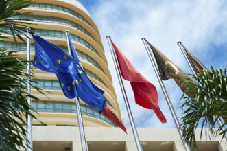 Flying colours (including EU) against modern building and blue sky