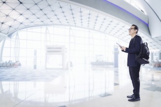 Junger Geschäftsmann mit digitalem Pad lächelnd glücklich im Flughafen warten Halle