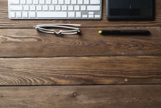 Top view office workspace composition. Flat lay vintage wooden desk with pc keyboard and graphic