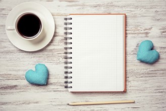 Coffee cup notepad pencil and two hearts on wooden surface