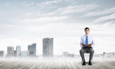 Young businessman with book on office chair