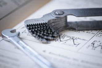 Detailed view of a fanned-out thread gauge with a small spanner lying next to it on an old