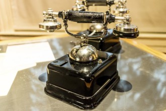 An antique analog telephone set with black box base and golden ringer, and handset