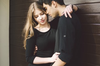Portrait of attractive Mixed-race couple standing together against the background of a wooden wall.