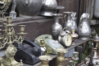 A vintage display of metallic jugs, candelabras, old phones, and a clock, Turkey