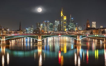 The illuminated skyline of the city centre of Frankfurt am Main at night and full moon with the
