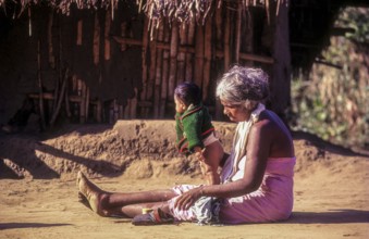 A jenu kurumba tribal old woman with her grandson. Baby urinating in Nagarahole tribal settlement