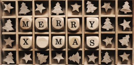 Small wooden dices in a box with the words Merry x-mas, star and tree shape decoration around