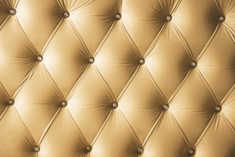 Beige soft textile background with symmetrical buttons on the corners of diamonds. Soft and
