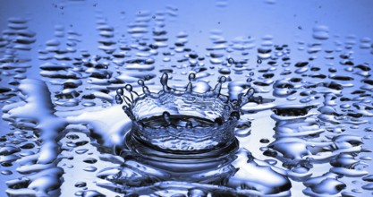 Drop of Water falling into Water against Blue background