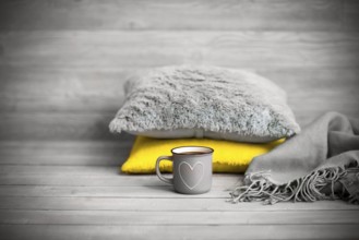 Pillows and cup of beverage against blurred wooden wall as symbol of warmth and comfort at home