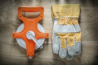 Pair of safety gloves Tape measure on wooden board